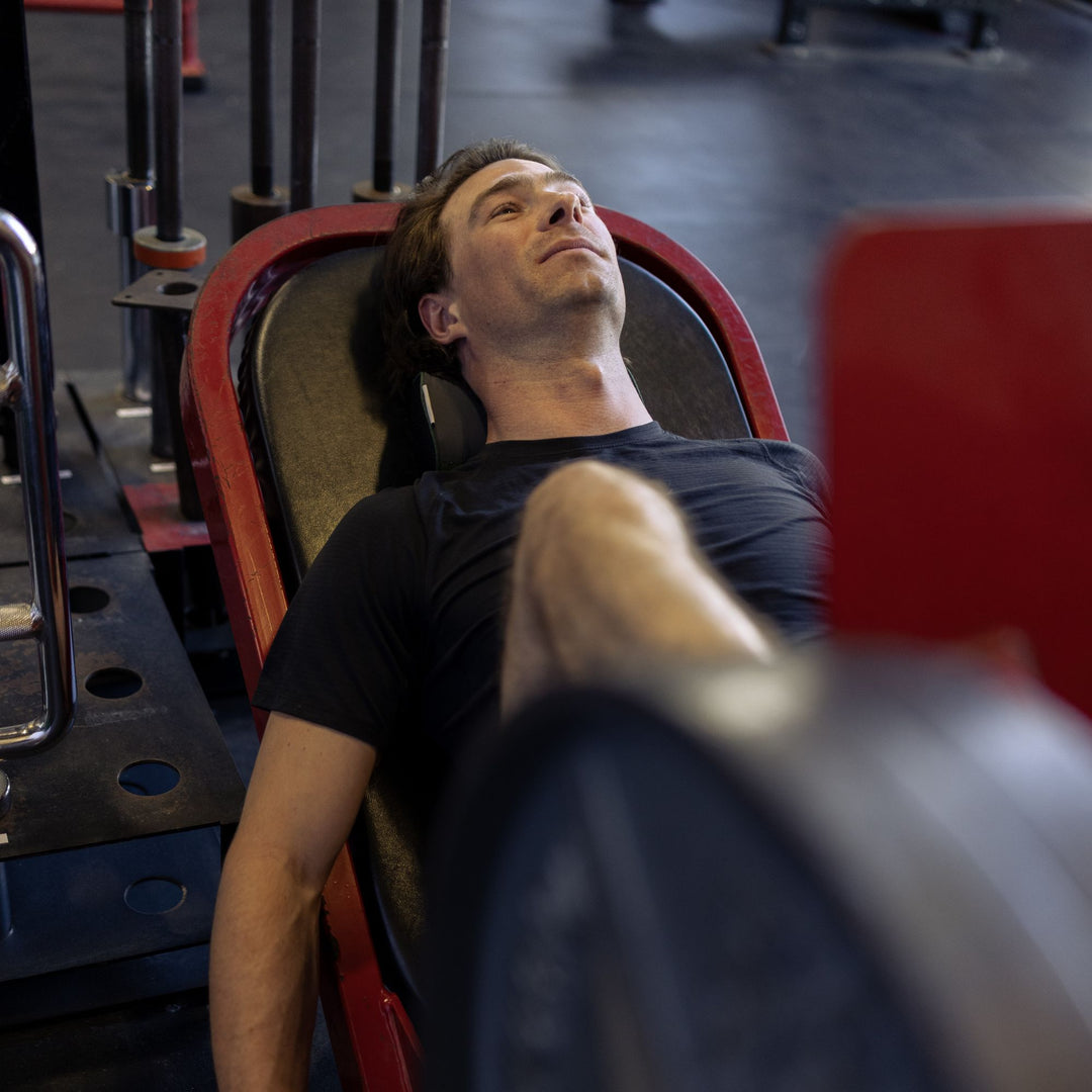Man lying on a leg press bench in a gym setting