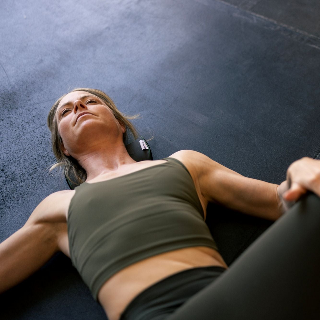 Woman lying on a dark mat and stretching hips