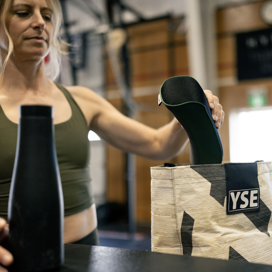 Woman in a gym setting putting the forteneck neck cushion in a travel bag